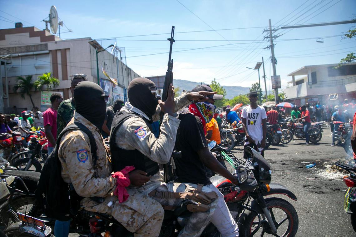 Armed and masked police officers move forward on a motorcycle during a protest by a disgruntled sector of the Haitian police force known as Fantom 509, in Port-au-Prince, Haiti, Wednesday, March 17, 2021. The protests started when officers and police academy cadets marched toward police headquarters to demand that the bodies of several officers killed during a raid last week on the Village of God shantytown be recovered from the gang still holding them.