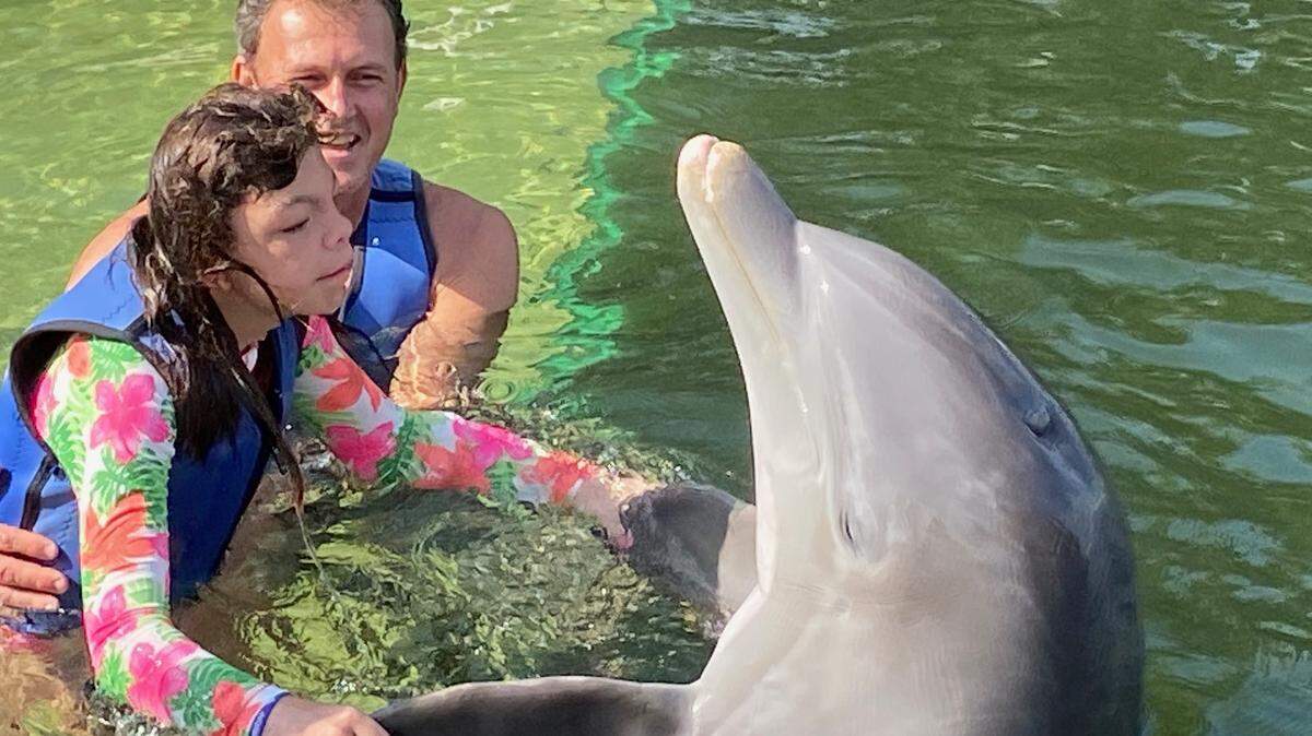 Giovanna Camarotti Dadalto holds the pectoral fins of Leo the dolphin as her father, Renan Dadalto, watches. The family went to Dolphins Plus in Key Largo Friday, April 23, 2021, as part of the Make-A-Wish South Florida program.