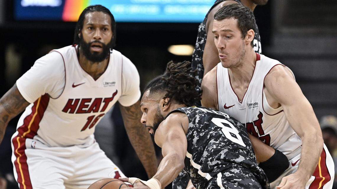 San Antonio Spurs’ Patty Mills, center, collides with Miami Heat’s Goran Dragic, right, as Miami forward James Johnson watches during the first half of an NBA basketball game Wednesday, March 20, 2019, in San Antonio.