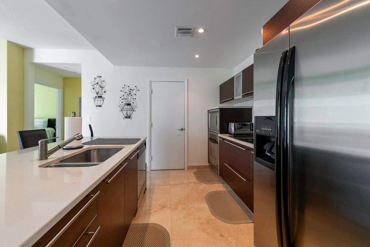 The kitchen, pictured above, features stainless steel appliances. It overlooks the living room and has direct views of the neighboring twin tower at Quantum on the Bay.