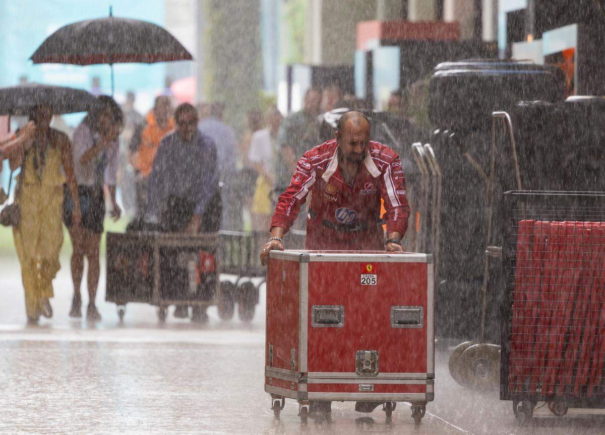 A Scuderia Ferrari crew member pushes equipment into his team’s garage as rain falls before the start of a Sprint race on the second day of the Formula One Miami Grand Prix at the Miami International Autodrome on Saturday, May 3, 2025, in Miami Gardens, Fla.