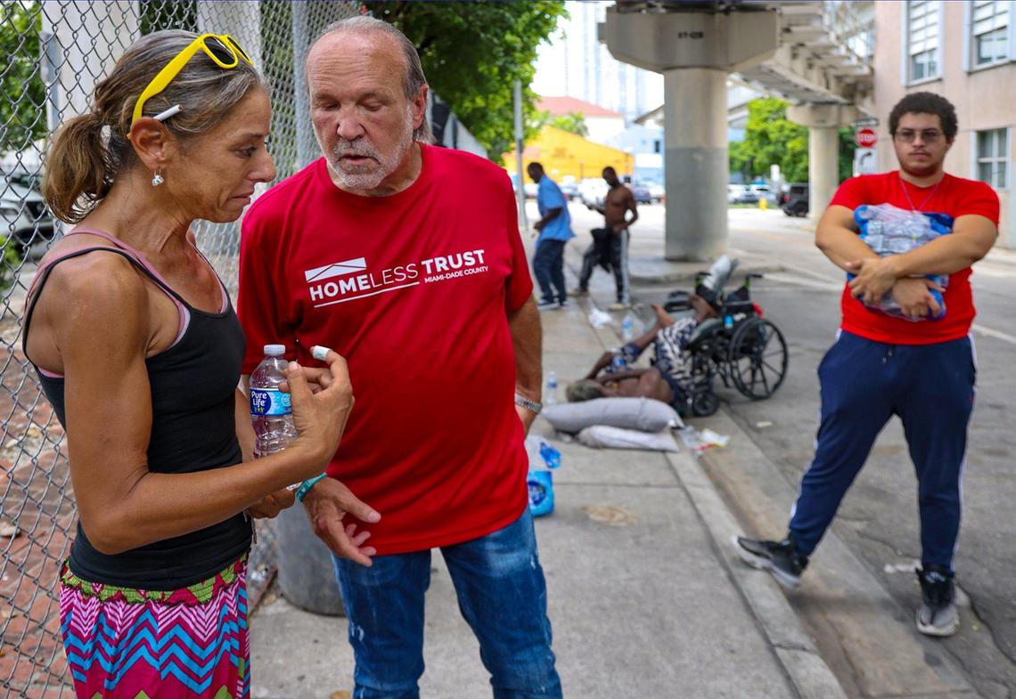 Amy Elyse Port, 47, left, emotionally retells an act of violence against her to Trust Chairman Ron Book, center, as outreach worker Robert Malpica, 19, right, from the Miami-Dade Homeless Trust, waits as they walked through downtown to survey the area and offer services to individuals on the street on Thursday, Aug. 1, 2024, in Miami.