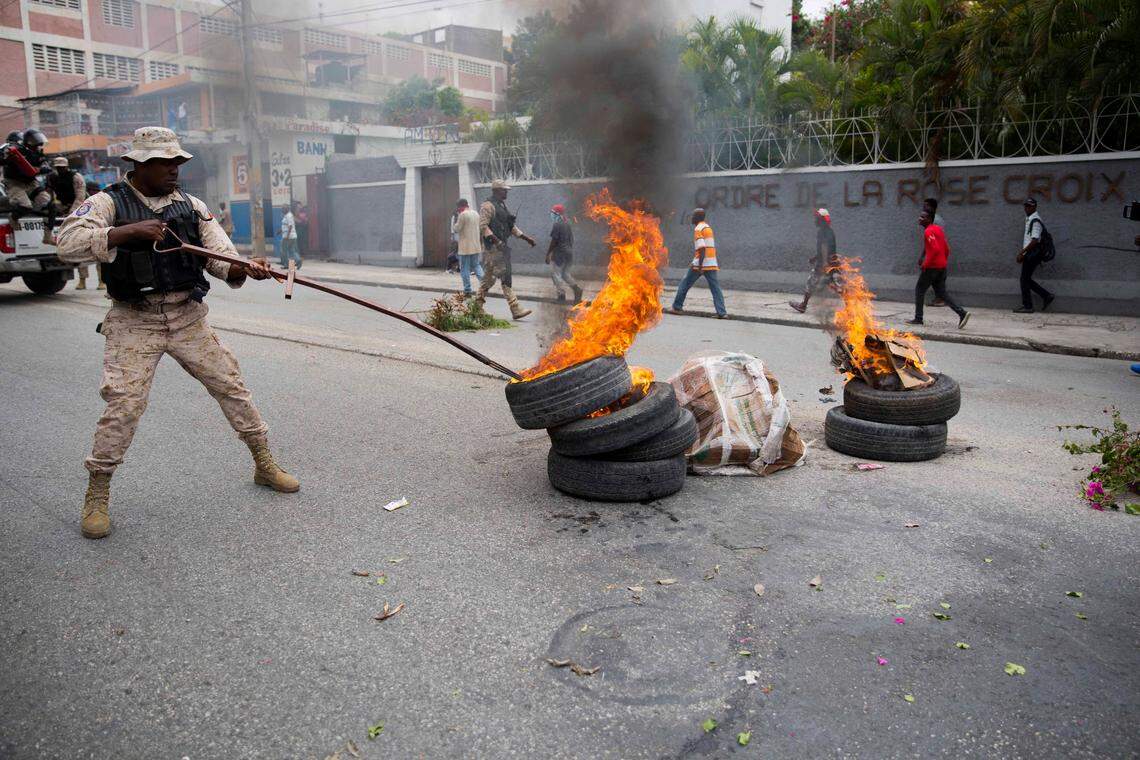 A police officer removes burning tires from a street during a demonstration demanding the resignation of Haitian President Jovenel Moise in Port-au-Prince, Haiti, Friday, March 29, 2019.