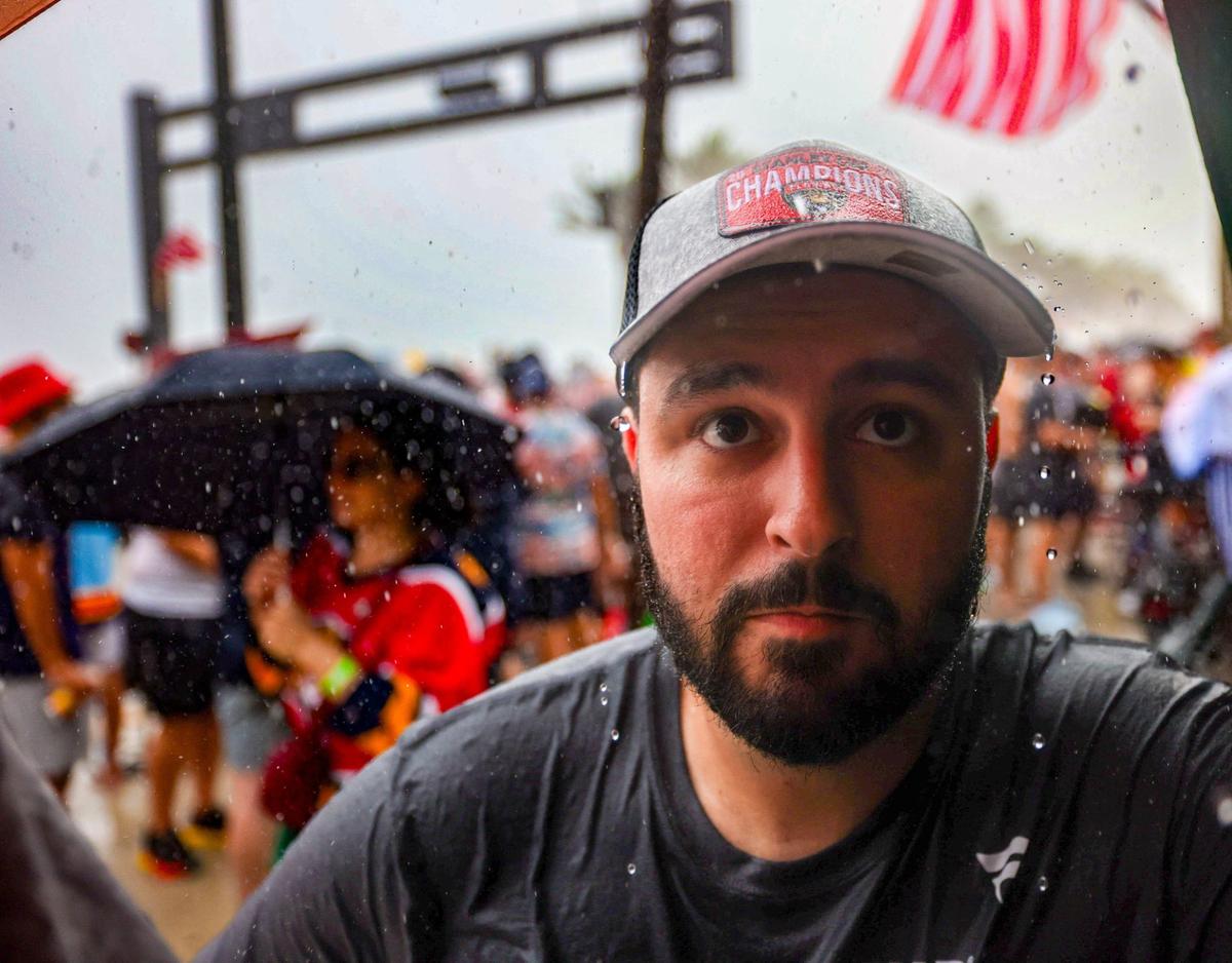 Rain drops fall off of the hat of Florida Panthers fan Brian Vazquez as he seeks cover under a balcony at Elbo Room as it started to storm in a Fort Lauderdale beach before the Florida Panthers victory parade before the Stanley Cup victory parade at Fort Lauderdale Beach on Tuesday, June 30, 2024 in Fort Lauderdale.&nbsp;