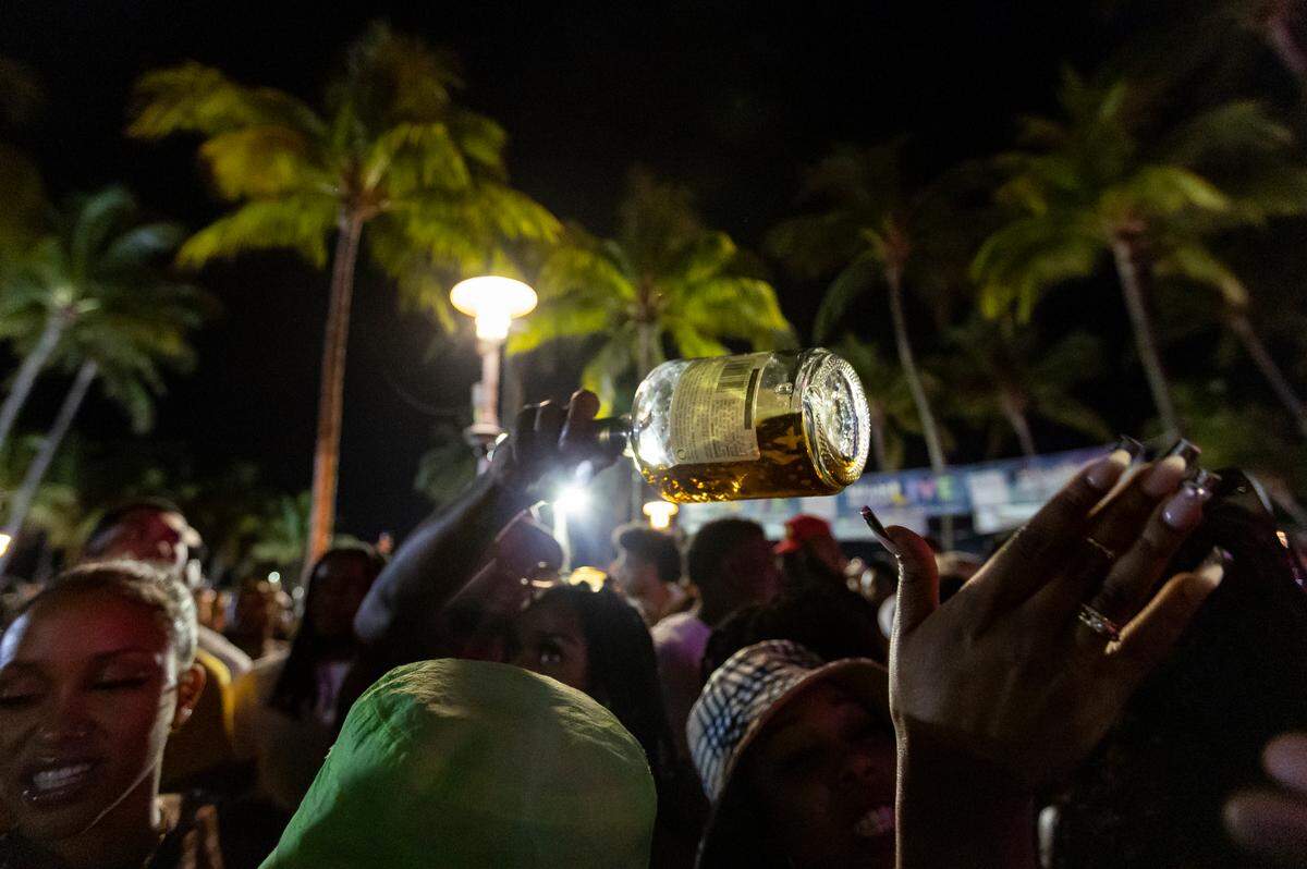 A bottle is passed around a crowd of people dancing on Ocean Drive during spring break on Saturday, March 11, 2023, in Miami Beach, Fla.