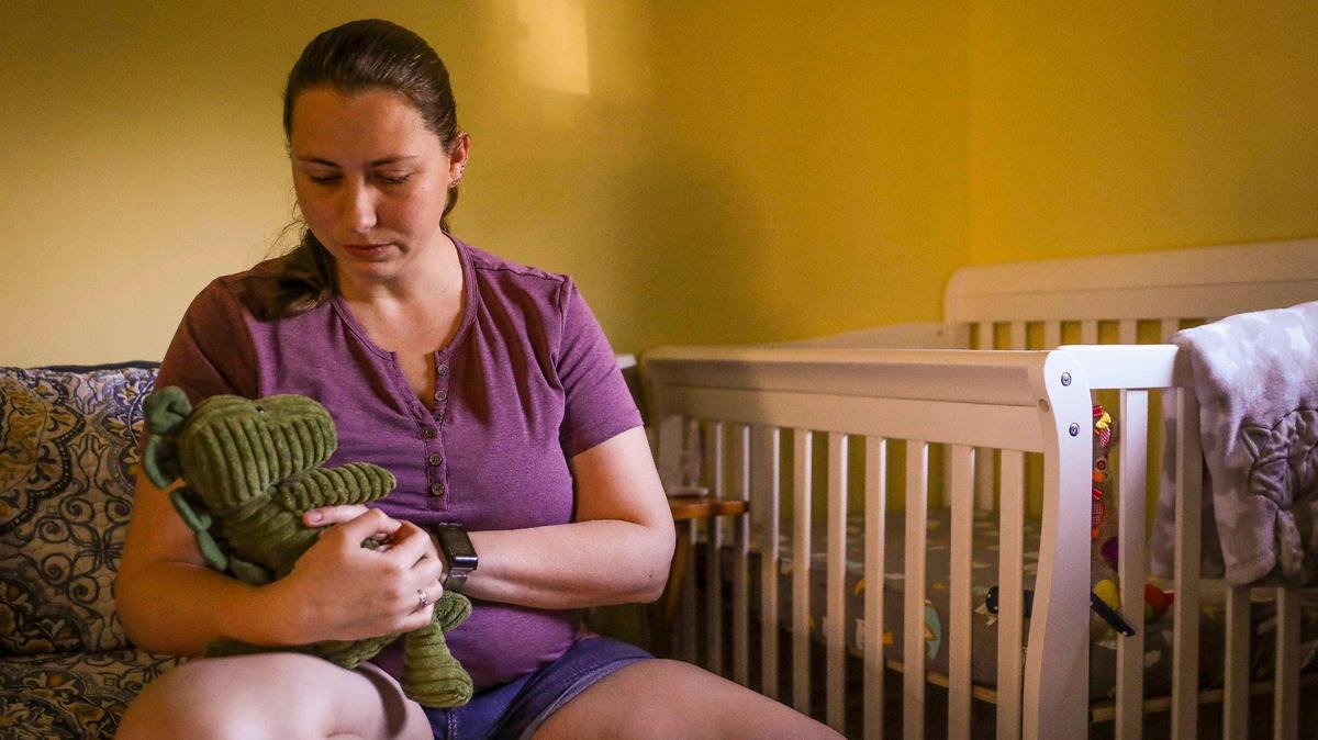 Danielle Tallafuss, de 35 años, posa con un dinosaurio de peluche que compró para Nathaniel, en su habitación el 21 de febrero de 2022. Danielle y su esposo decidieron interrumpir su embarazo a las 22 semanas para proteger a su hijo de los estragos que le causaría su enfermedad tras enterarse que Nathaniel tenía un defecto del 
 corazón