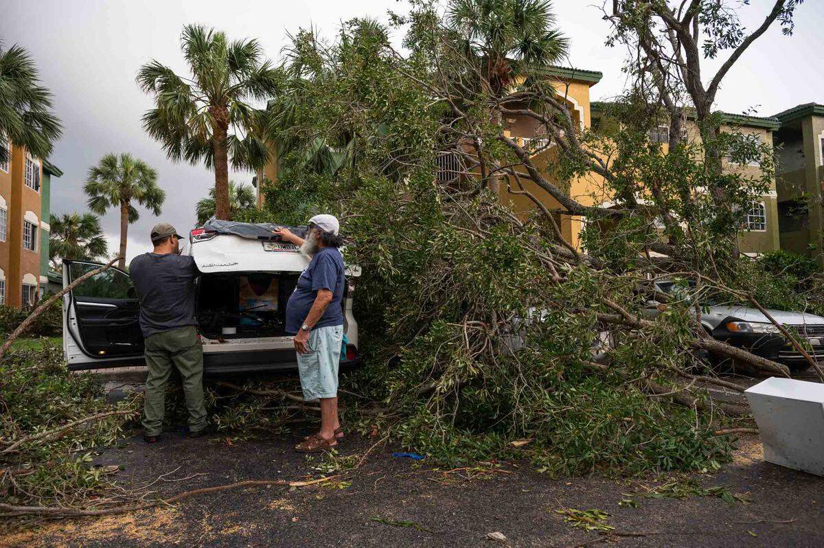 Samuel Tavarez, a resident at the Sanctuary Cove Apartment complex, attempts to cover the shattered windows of his car with tape and plastic tarp while being assisted by his father, Samuel Tavarez Sr., in the aftermath of a Saturday evening tornado on Sunday, April 30, 2023, in Palm Beach Gardens, Fla. The National Weather Service confirmed an EF-1 tornado touched down in Palm Beach Gardens Saturday evening.