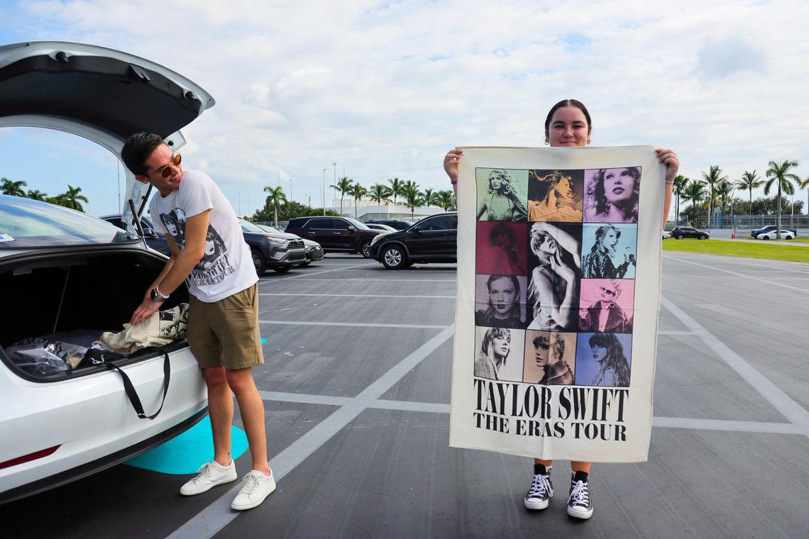Gleimy Barroso holds a Taylor Swift poster as Richard Perez watches from the parking lot after visiting the Taylor Swift Eras Tour merchandise store at Hard Rock Stadium in Miami Gardens, Florida, Wednesday, October 16, 2024.