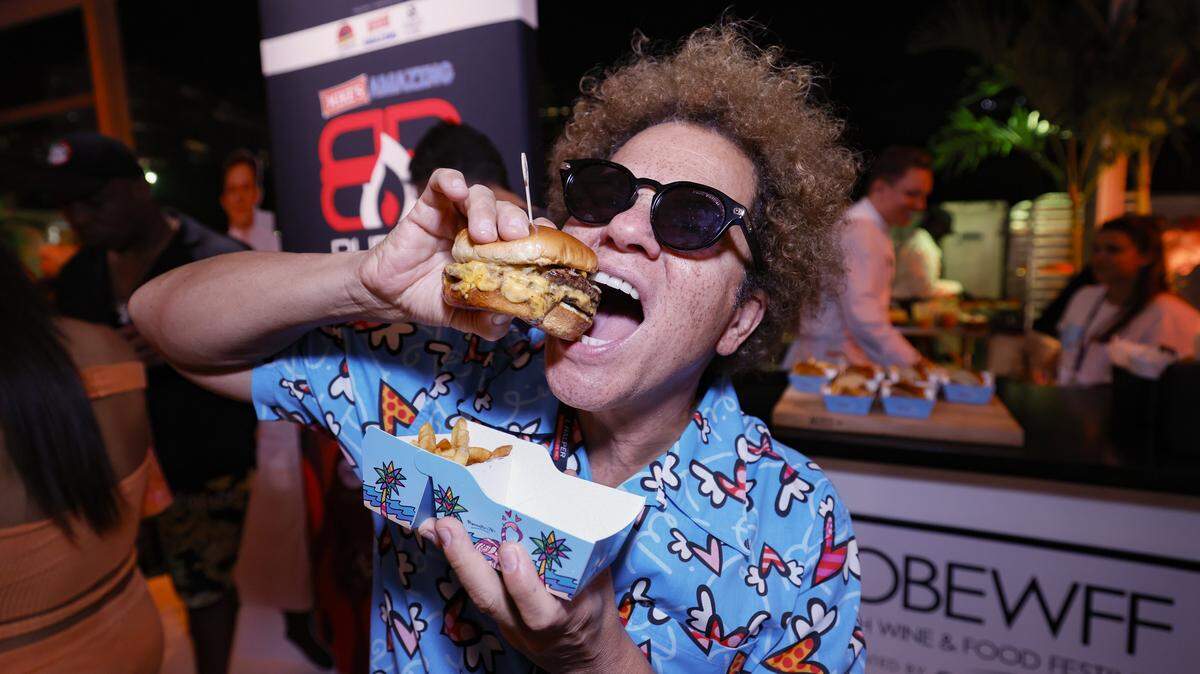 Romero Britto takes a bite out of a burger during the annual Burger Bash hosted by Rachael Ray as local burger restaurants compete to make the best burgers on Thursday, February 19, 2026.