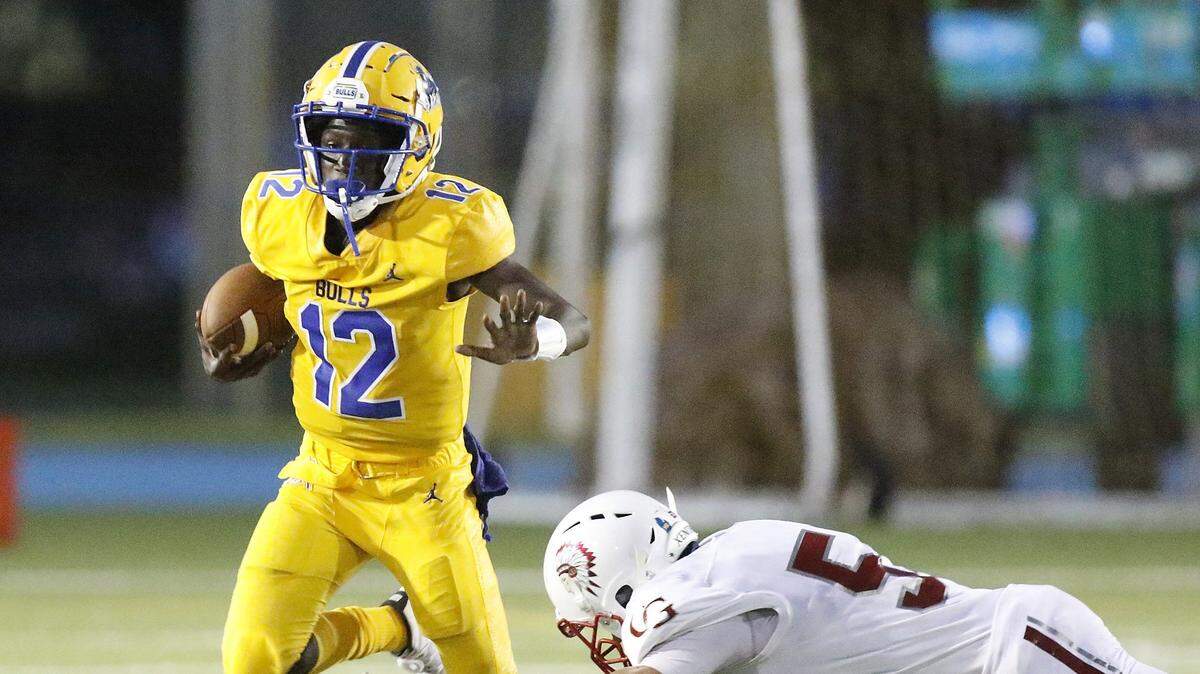 Northwestern Bulls’ quarterback Kemani Brown (12) tries to escape Cardinal Gibbons Chiefs’ defender during the football game on Friday, Aug. 23, 2019 at Traz Powell Stadium in Miami