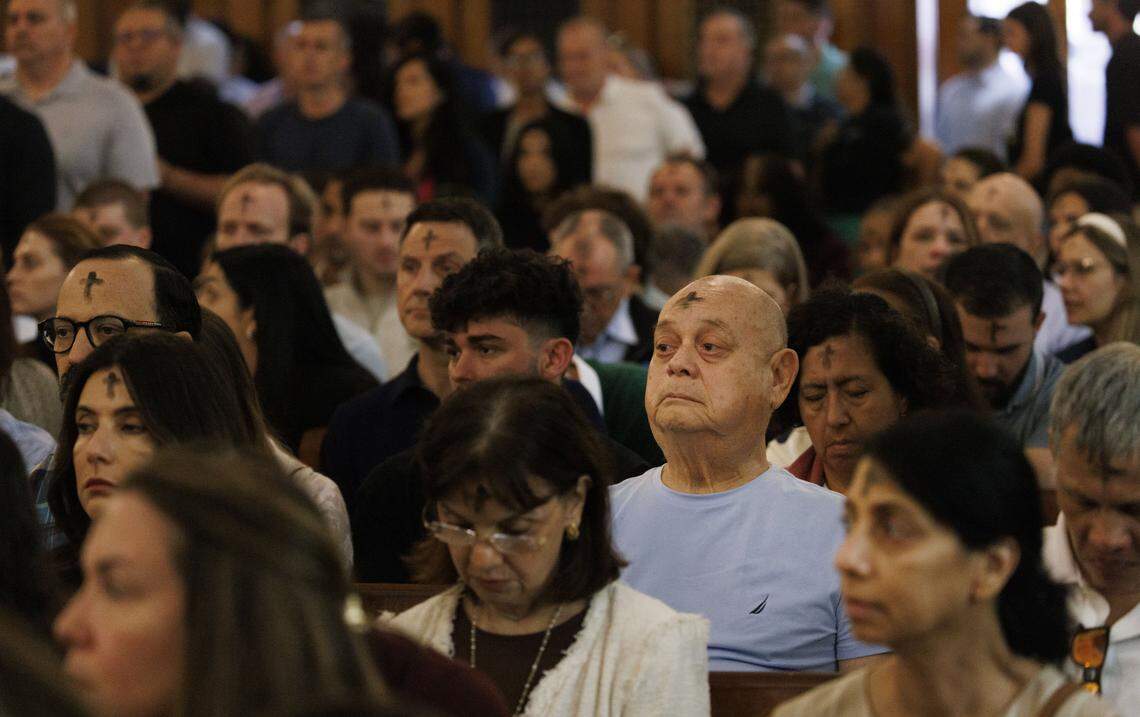People reflect after receiving ashes on their foreheads during Ash Wednesday mass on Wednesday, Feb. 18, 2026, at Gesu Catholic Church in downtown Miami. 