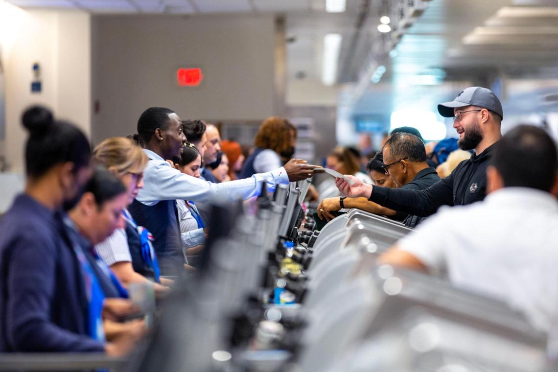 Un viajero toma su boleto del personal del aeropuerto en el nivel de salidas dentro del Aeropuerto Internacional de Miami el miércoles 23 de noviembre de 2022.