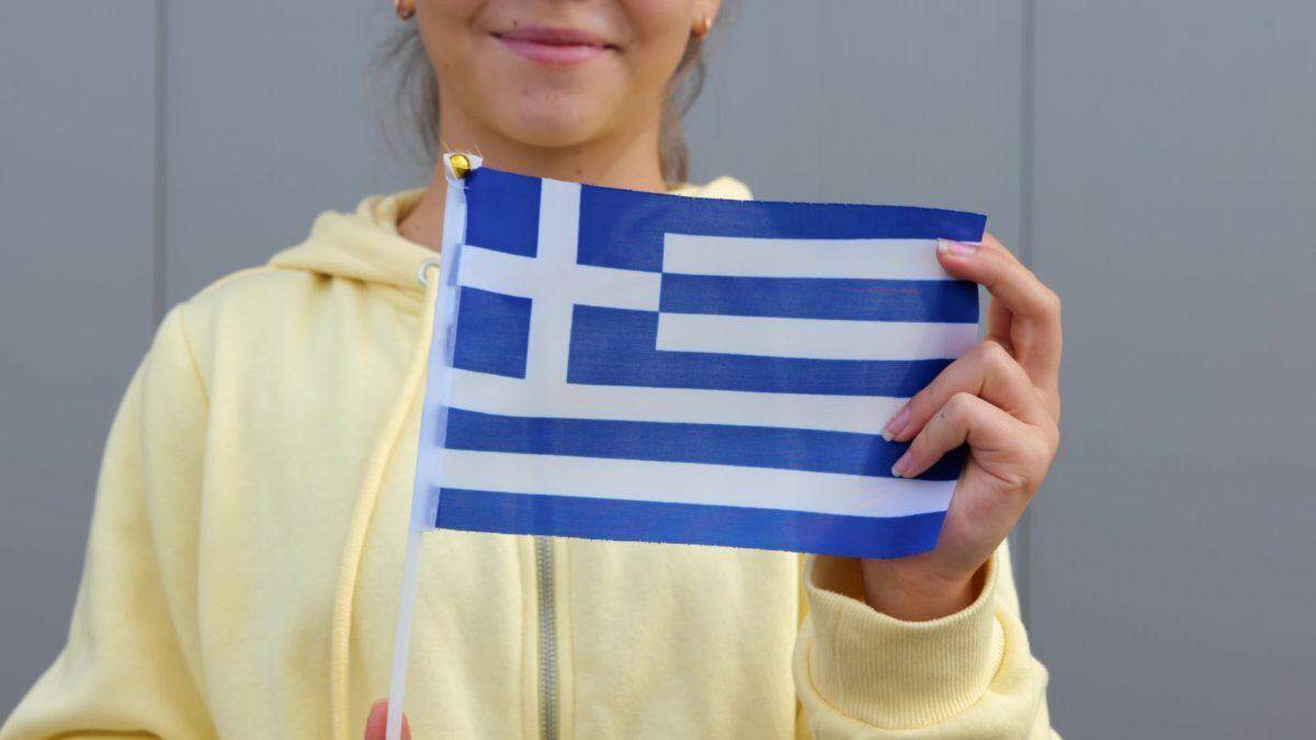 young woman holding small greece flag