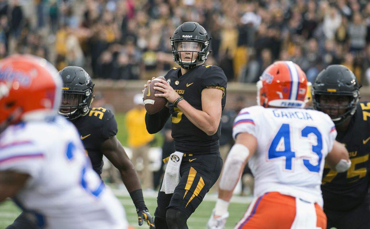 FILE - In this Nov. 4, 2017, file photo, Missouri quarterback Drew Lock looks for an open receiver between Florida defenders during the first half of an NCAA college football game in Columbia, Mo. Missouri (4-5, 1-4) is building off of a 45-16 trouncing of Florida last weekend. Lock threw for 228 yards, three touchdowns and an interception on 15-for-20 passing in the win, and the Tigers rushed for 227 yards. Missouri plays Tennessee this week. (AP Photo/L.G. Patterson, File)