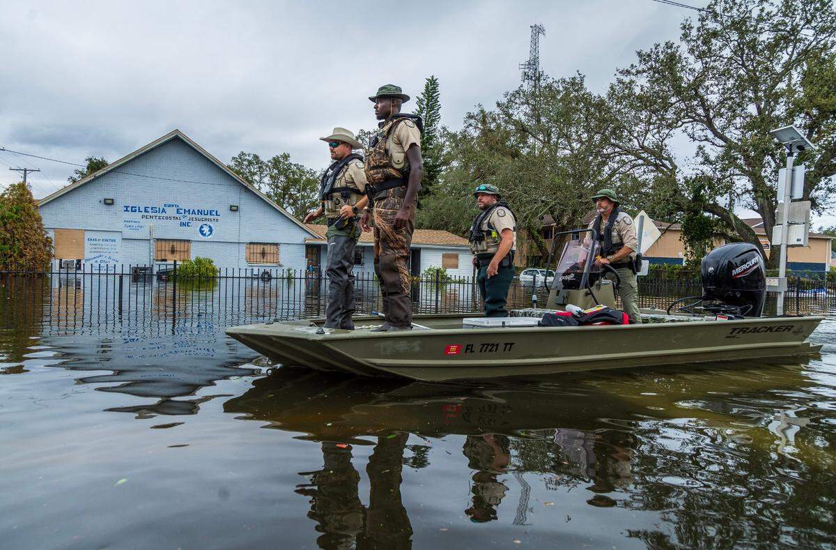 Florida Fish and Wildlife Conservation Commission officers ride a flats boat through the flooded N 12th St in North Tampa, on Thursday, October 10, 2024, a day after Hurricane Milton crossed Florida’s Gulf Coast.
