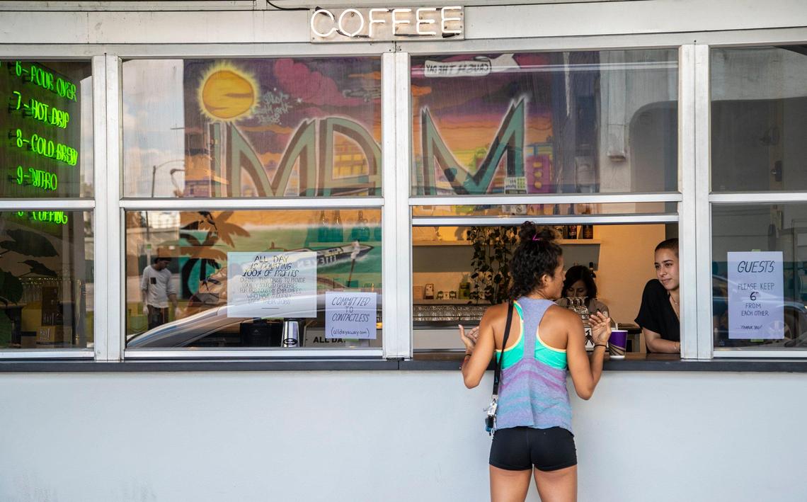 Picking up her coffee order is Olivia Rosal as she speaks to Daniela Llanes working at All Day, a coffee shop and restaurant in downtown Miami. Due to COVID-19 many restaurants have adjusted their hours and offer expanded services for pick up or delivery and several are turning to selling groceries that would be otherwise stuck up the supply chain at farms, dairies and ranches.