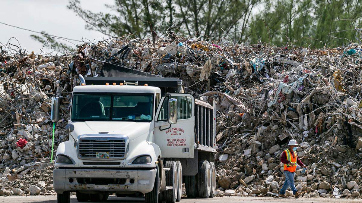 Trabajadores apilan escombros y los restos del derrumbe de Champlain Towers South dentro de un terreno cerca del Aeropuerto Internacional de Miami en la esquina de Milam Dairy Road y NW 12 Street, en Miami, Florida, el 10 de julio de 2021.