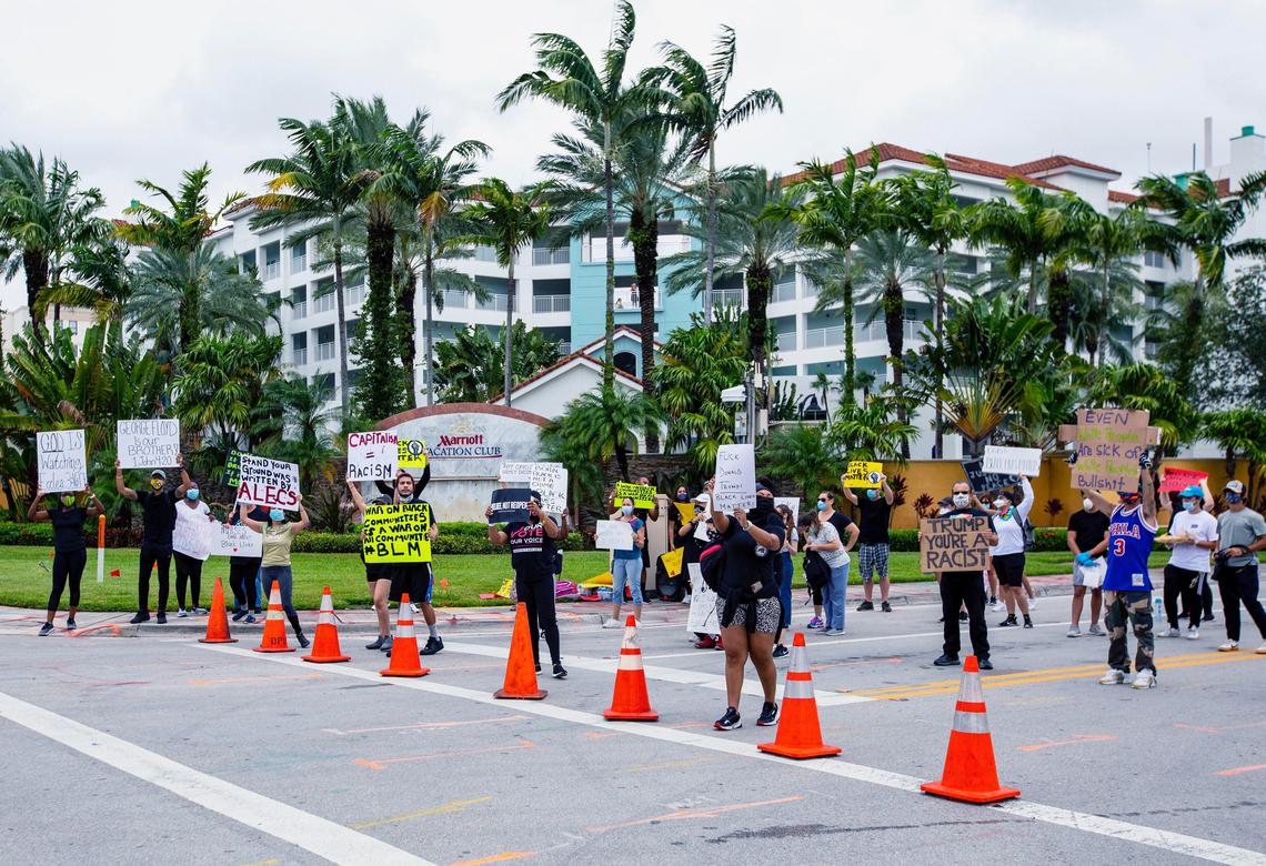 Protesters chant and hold up signs as they demonstrate across the street from Trump National Doral during a Justice for George Floyd protest on Saturday, June 6, 2020.