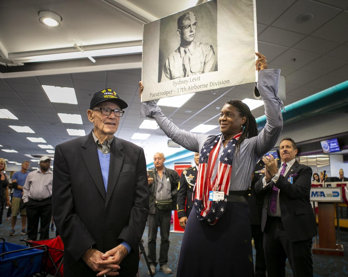 Paula Jarrett, the Honor Flight South Florida committee chair, holds a photograph of Sydney Levit, 94, during his sendoff celebration at the Miami International Airport on Wednesday, May 22, 2019. Levit will be the only World War II veteran representing America as a guest of honor at the Memorial Day 75th Anniversary Ceremony at the Cambridge American Cemetery in England.