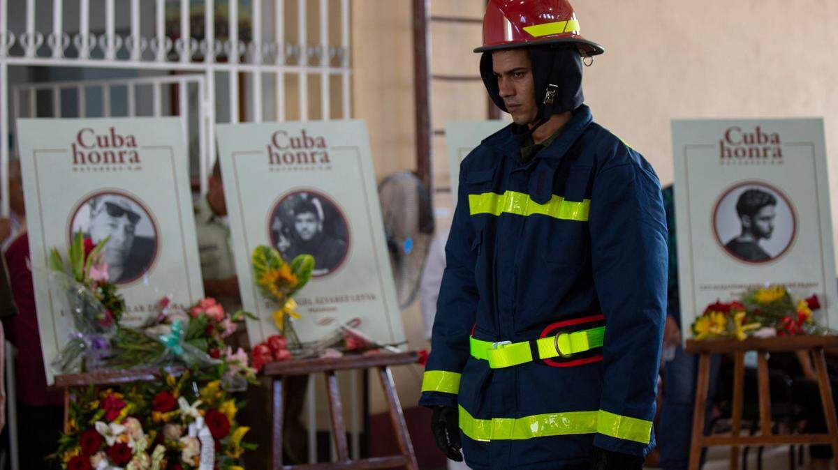 A firefighter walks past photos and caskets of those who died in the fire at the Matanzas Supertanker Base, an oil storage facility, during a funeral ceremony inside the Firefighters Museum in Matanzas, Cuba, Friday, Aug. 19, 2022. Lightning sparked the fire on Aug. 5 and killed 16 people, injured more than 100, destroyed four of the facility’s eight tanks and forced almost 5000 people to evacuate.