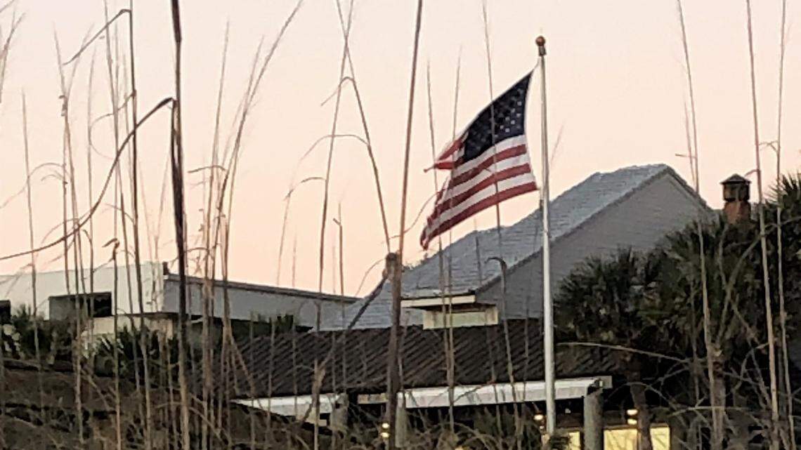 A tattered American flag flies at sunrise on a Florida beach.