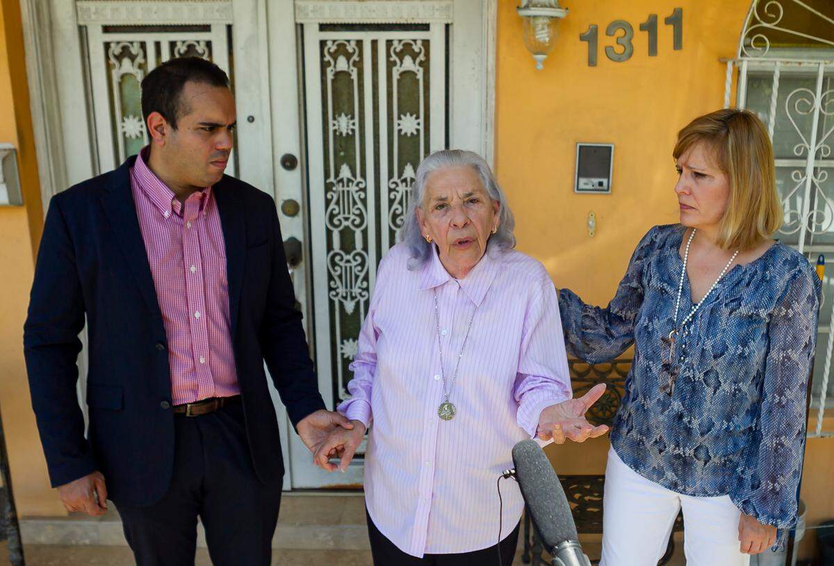 Ana Lazara Rodriguez, 82, center, surrounded by Eleazar Melendez, left, and Laura Wagner, right, speaks during a press conference outside of her home in Miami, Florida on Thursday, May 6, 2021.