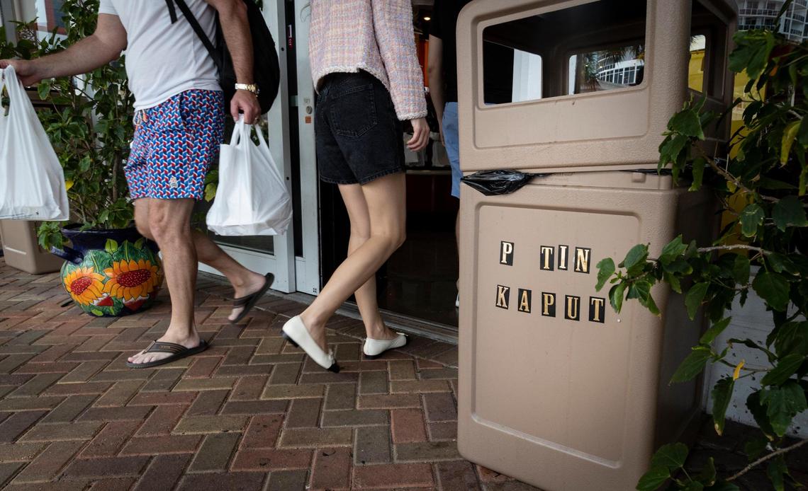 A sign on a garbage can at the entrance of Matryoshka grocery and deli in Sunny Isles Beach reads “Putin Kaput.”