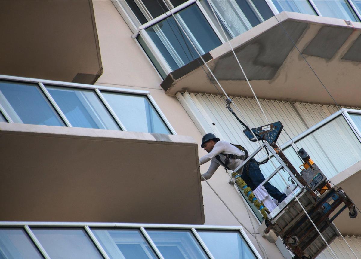 Workers do repairs on the exterior of the Mirage condo in Surfside on Oct. 7. An engineer’s 2018 report detailed damage in the tower’s balconies and pool deck.