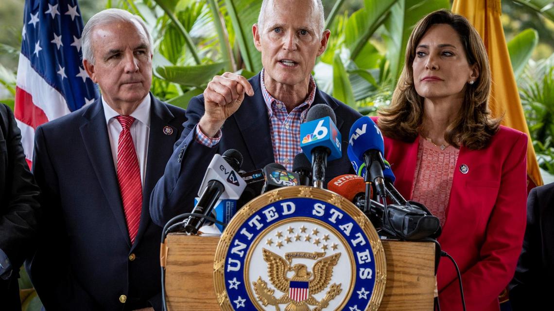 Sen. Rick Scott speaks during a press conference in front of Mondongo’s Restaurant in Doral, flanked by U.S. Reps. Carlos Gimenez, left, and Maria Elvira Salazar, right.