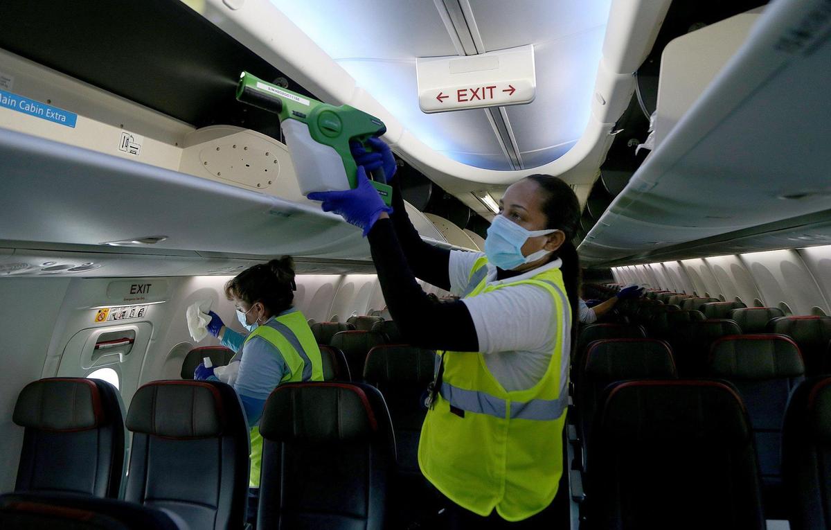 Wendy Valdez, an American Airlines employee, uses an electrostatic fogger during an on-board American Airlines aircraft cleaning process before departing from Miami International Airport on Tuesday, June 30, 2020. American Airlines hosted the media to highlight their new sanitizing methods as they boost passenger capacity on their flights amid a surge of new COVID-19 cases in Florida and across the country.
