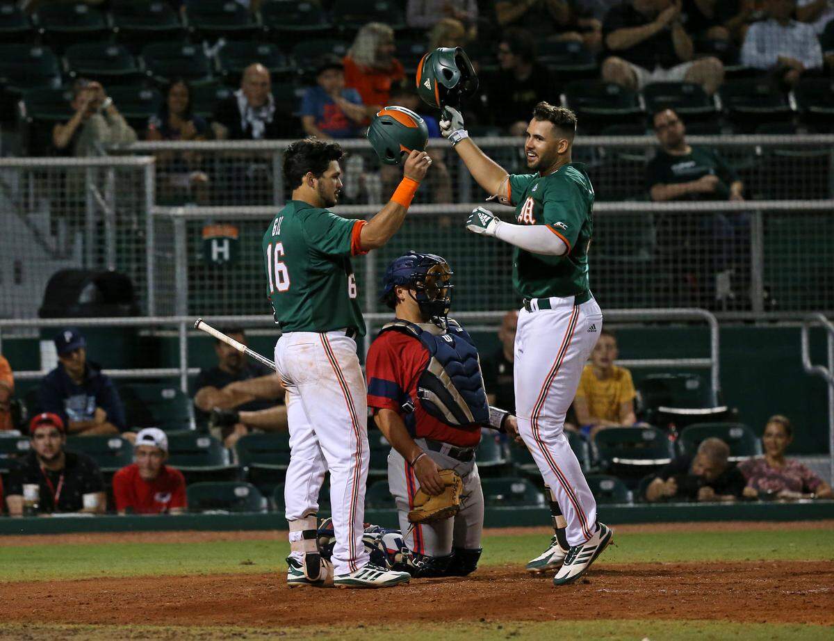 Miami Hurricanes first baseman Alex Toral (30) is congratulated by third baseman Raymond Gil (16) after hitting a solo home run during the sixth inning of a NCAA baseball game against the Florida Atlantic University Owls at Alex Rodriguez Park at Mark Light Field on Wednesday, February 20, 2019 in Coral Gables.