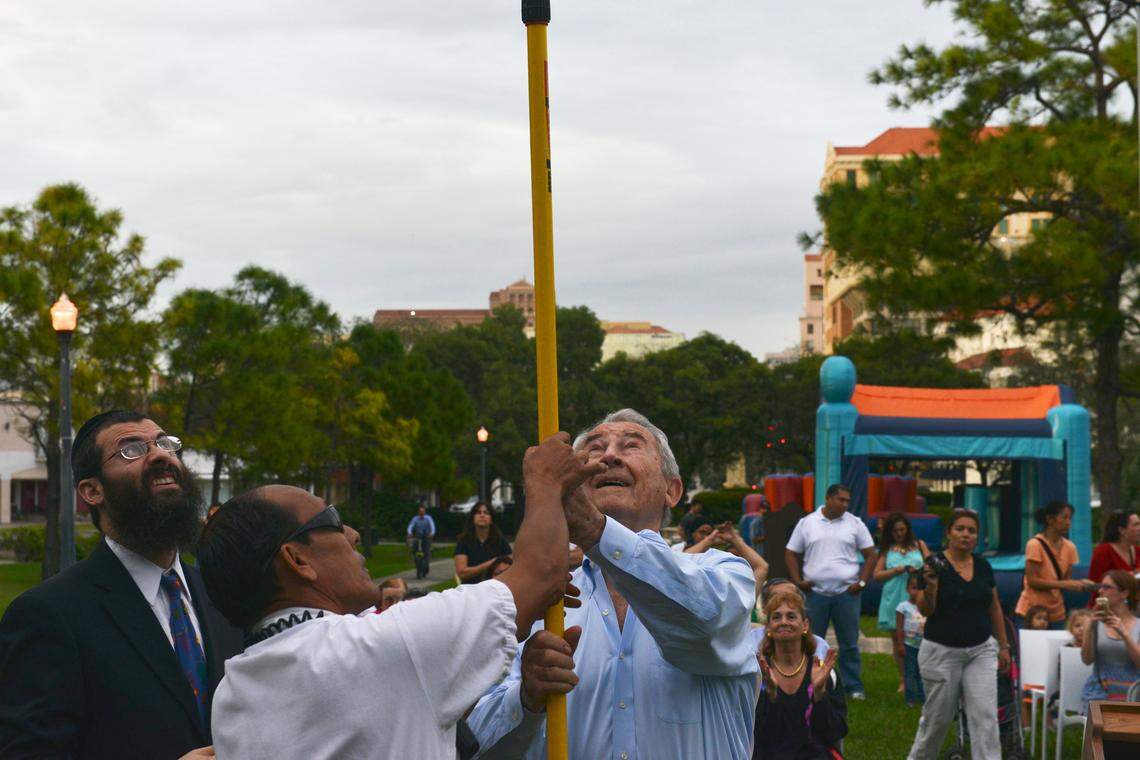 David Schaecter, right, the president of the Holocaust Survivors Foundation of the U.S., lights the menorah while rabbi Avrohom Stolik watches during the City of Coral Gables Menorah Lighting ceremony and Chanukah celebration at Ponce Circle Park on Sunday, Dec. 1, 2013. Schaecter is also a founding member of the Holocaust Memorial of Coral Gables, Fla.