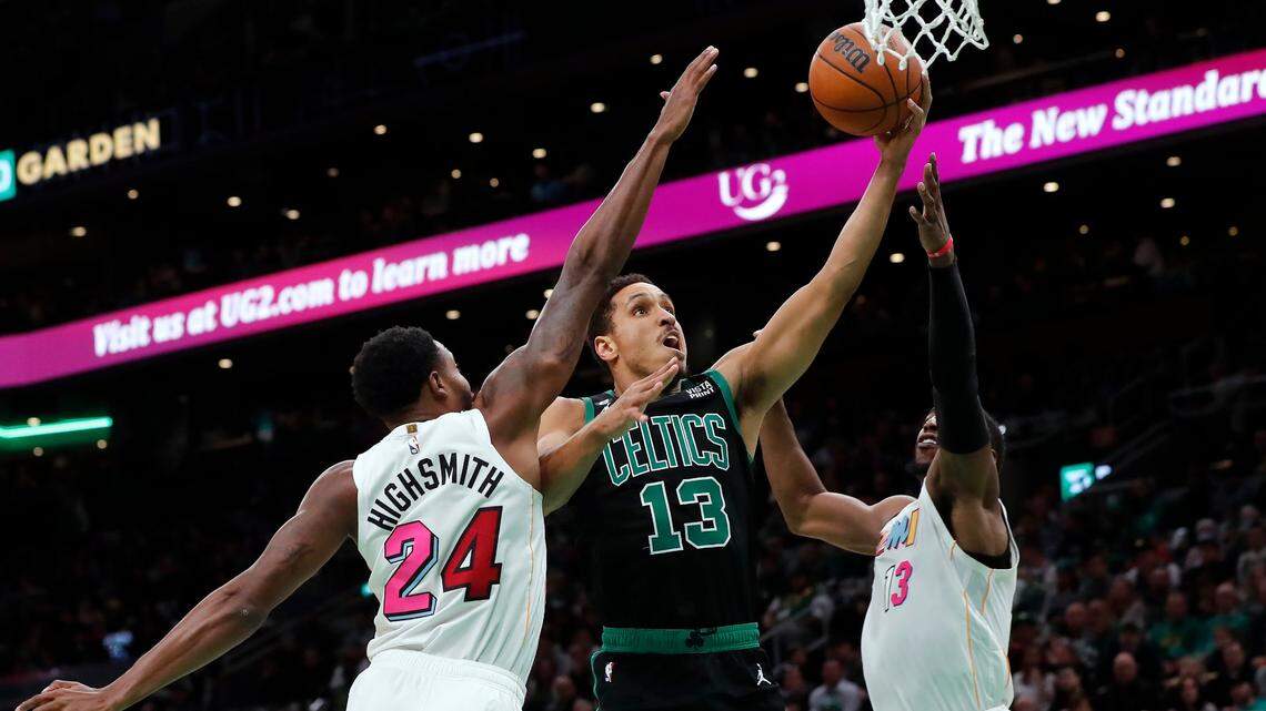 Boston Celtics’ Malcolm Brogdon, center, shoots against Miami Heat’s Haywood Highsmith (24) and Bam Adebayo, right, during the first half of an NBA basketball game Friday, Dec. 2, 2022, in Boston.