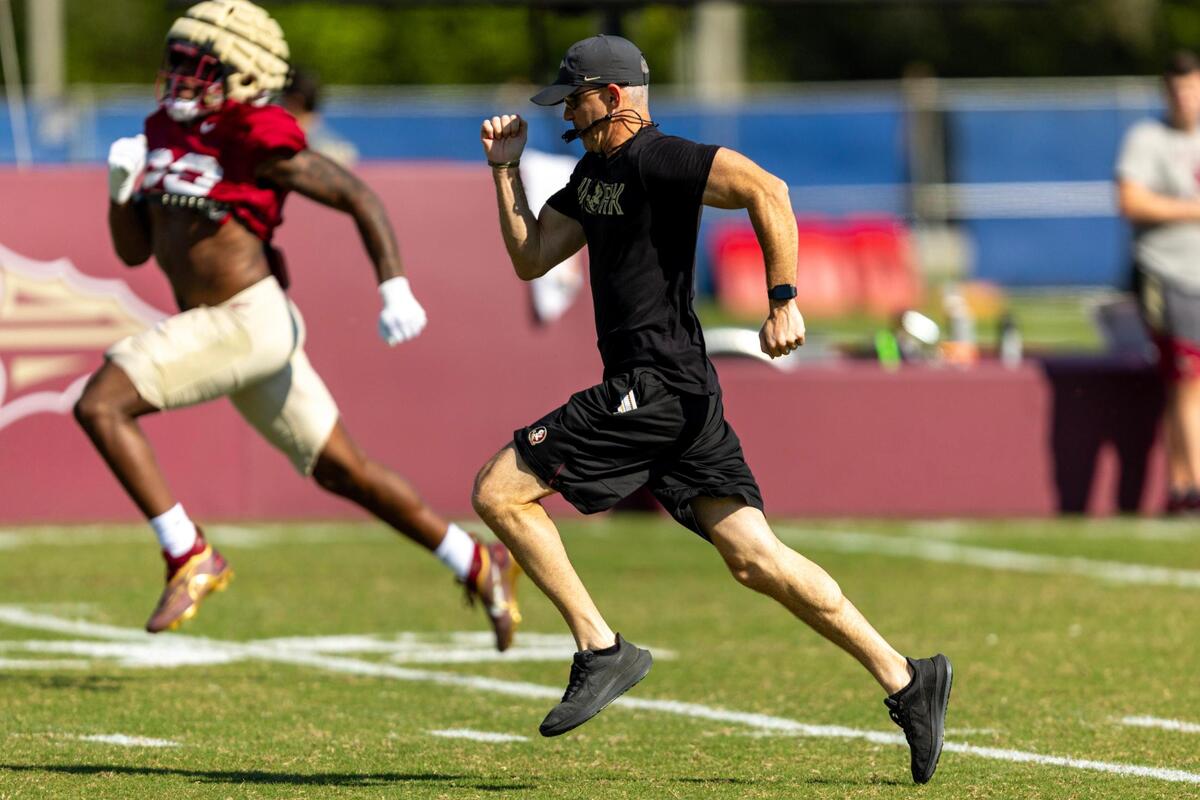 FSU coach Mike Norvell races a player during practice Wednesday at Nova Southeastern University in Davie.