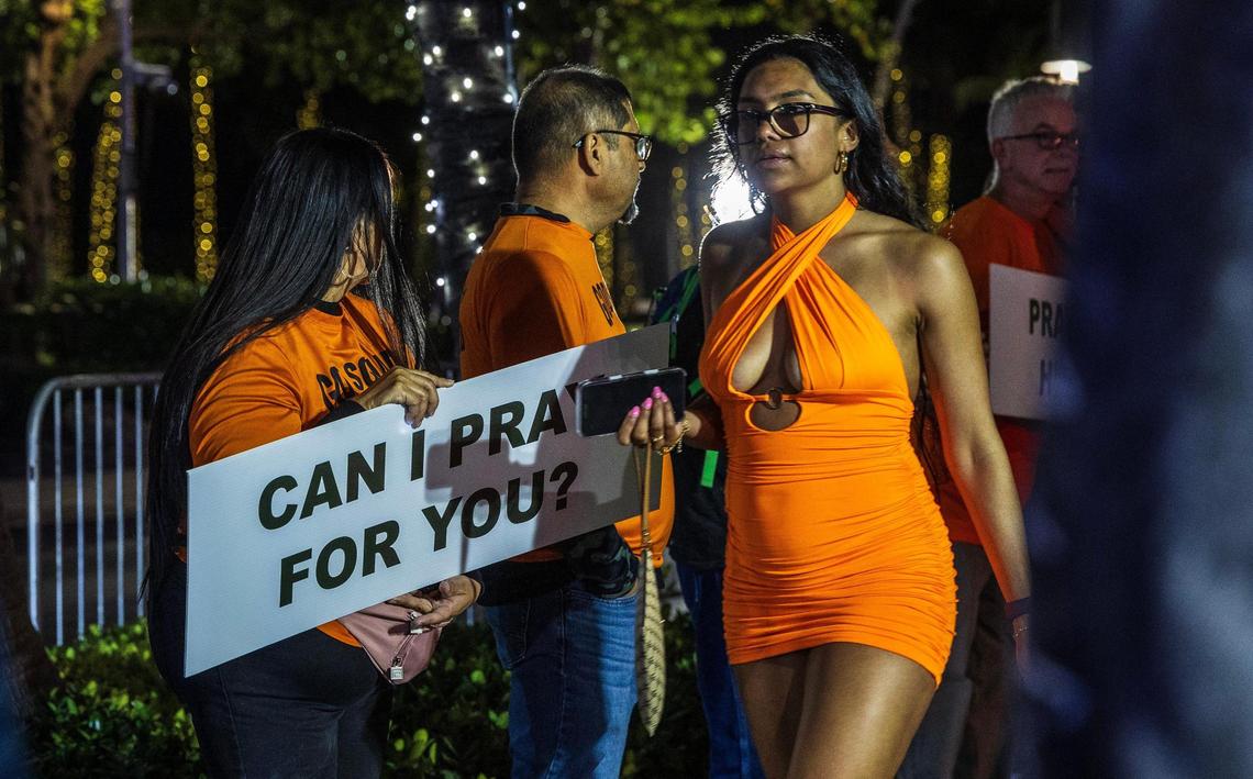 Members of the God Squad offer to pray for people making their way up Ocean Drive at night during spring break in Miami Beach, Florida, on Friday, March 21, 2025.