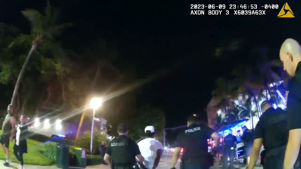 A screenshot from body-camera footage shows Fred Johnson, center in the white shirt, being taken away to jail by Miami Beach police officers.