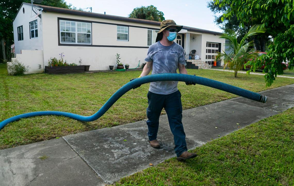 Jeremy Langford, an employee at AA ARON Super Rooter, center, puts away a hose after cleaning a septic tank at a home in Miami, Florida on Wednesday, September 30, 2020.