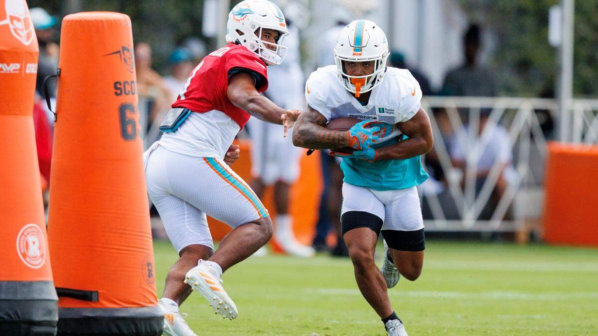 Miami Dolphins quarterback Tua Tagovailoa (1) hand off the football to Dolphins running back Myles Gaskin (37) during NFL football training camp at Baptist Health Training Complex in Hard Rock Stadium on Sunday, August 7, 2022 in Miami Gardens, Florida.