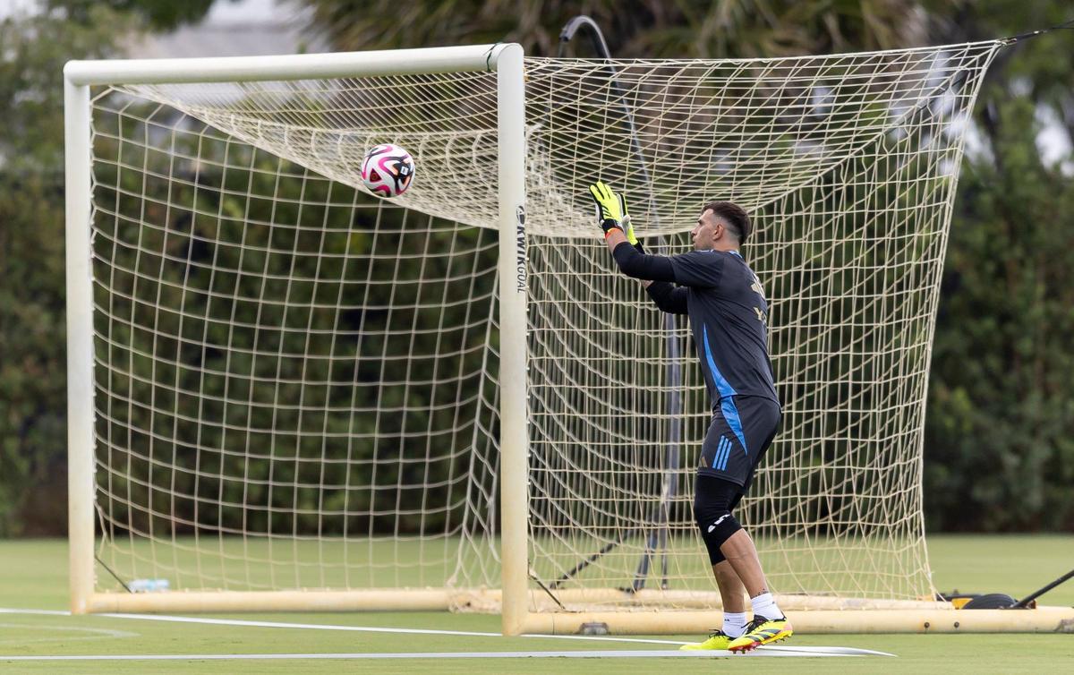 Argentina’s goalkeeper Emiliano Martínez catches a soccer ball while running drills with his teammates.