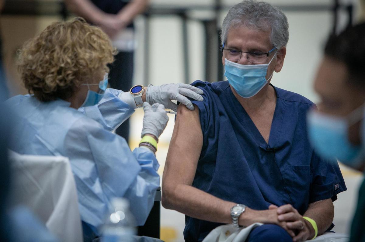 El doctor Sergio Segarra, director médico del Baptist Hospital of Miami, a la derecha, recibe la vacuna contra COVID-19 cuando Baptist Health comenzó a administrar las primeras vacunas COVID-19 para sus trabajadores de salud de primera línea en Miami, Florida, el 16 de diciembre de 2020.
