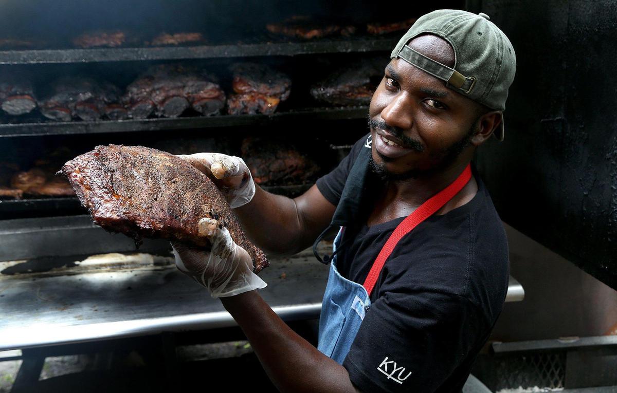 Chef Mark Wint holds a piece of brisket just out of the barbecue pit at The Drinking Pig. Wint is the sous chef at Wynwood’s Kyu, an upscale Asian barbecue restaurant.