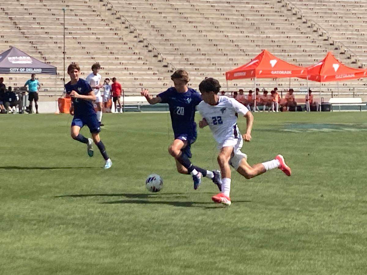 Florida Christian’s Marcelo Gomez (20) races Duncan MacKenzie to a loose ball during Thursday afternoon’s 2A boys soccer state semifinal at Spec Martin Stadium in DeLand.