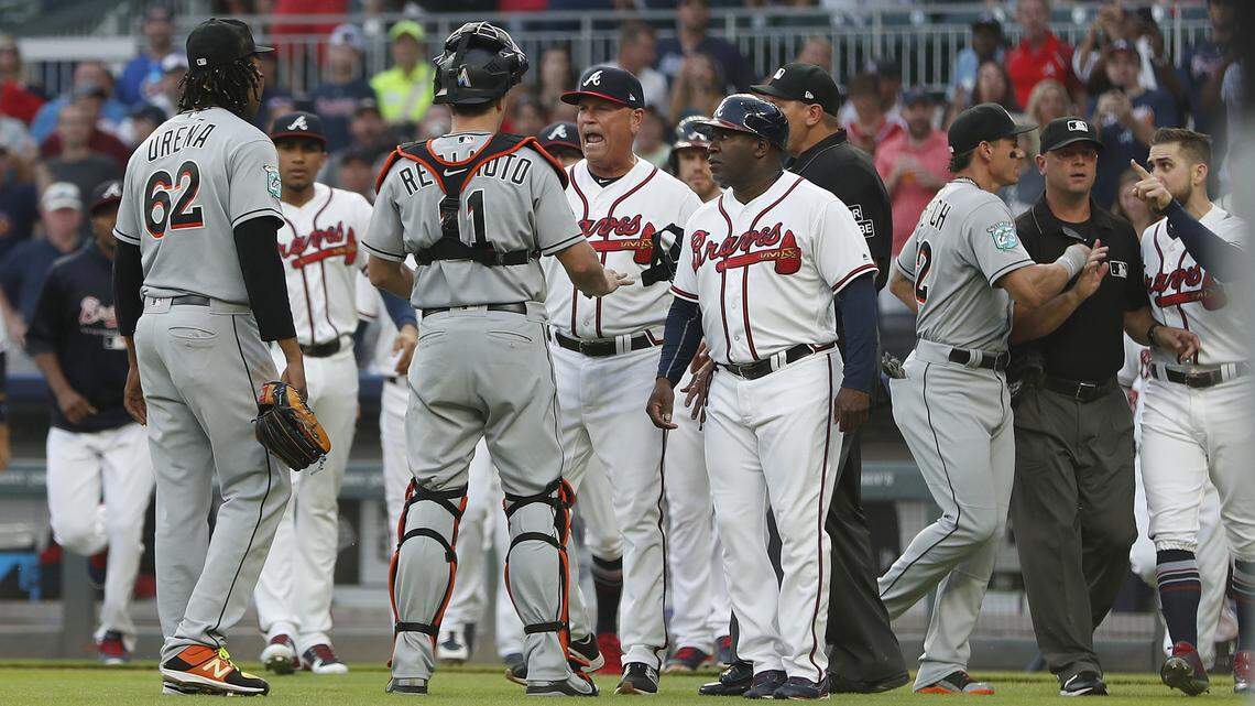 Miami Marlins catcher J.T. Realmuto (11) stands between pitcher Jose Urena (62) and Atlanta Braves manager Brian Snitker (43) as the dugouts empty after Urena hit Braves’ Ronald Acuna Jr. with a pitch during the first inning of a baseball game Wednesday, Aug. 15, 2018m in Atlanta. Marlins’ Derek Dietrich (32) and Braves’ Ender Inciarte argue at right. (AP Photo/John Bazemore)