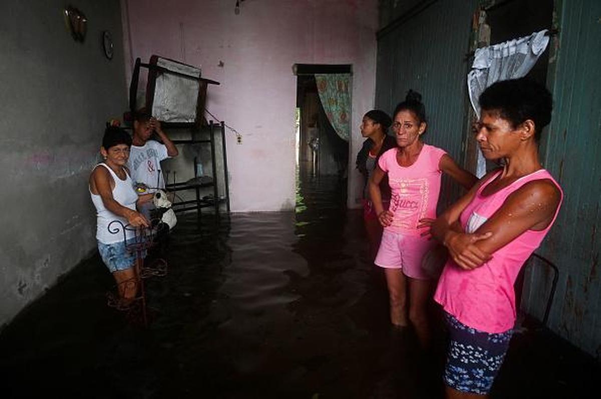 A family is seen inside their flooded home in Batabano, Cuba, on September 27, 2022, during the passage of hurricane Ian. - Hurricane Ian made landfall in western Cuba early Tuesday, with the storm prompting mass evacuations and fears it will bring widespread destruction as it heads for the US state of Florida. (Photo by YAMIL LAGE / AFP) (Photo by YAMIL LAGE/AFP via Getty Images)