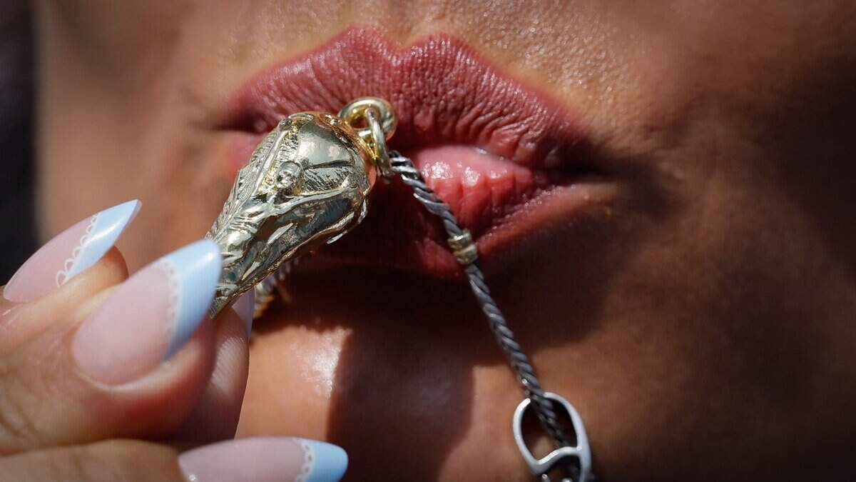 Maria Fernandez kisses her world cup necklace charm before the start of the FIFA World Cup 2026 Round of 32 soccer match between Argentina and Cape Verde at Hard Rock Stadium (Miami Stadium) on Friday, July 3, 2026, in Miami Gardens, Fla.