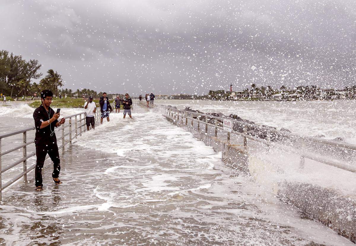 A Jupiter residents along with Ernesto Carmelo, 25, left, take pictures as large waves crash against the jetty at the Jupiter Inlet while Hurricane Dorian started traveling north about 100 miles off the Florida Coast on Tuesday, September 3, 2019.