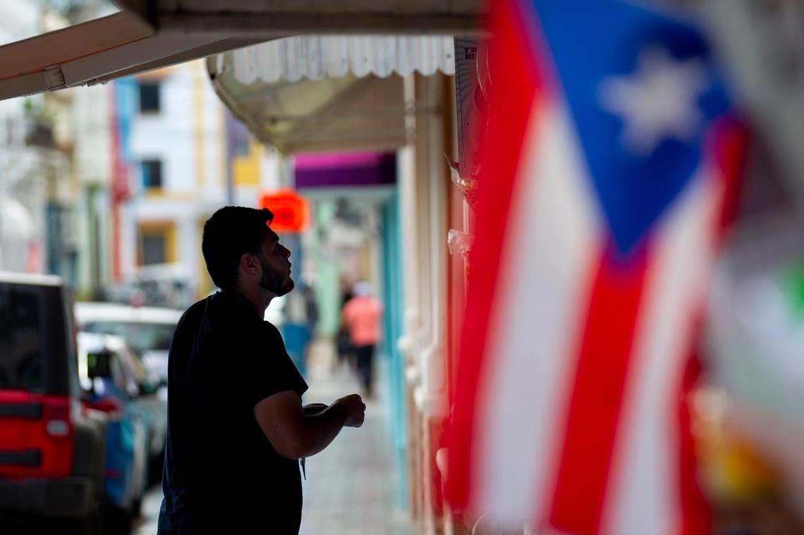 Manuel Perez, an employee at a beauty shop in Utuado, Puerto Rico, hangs a sign on August 22, 2018. Perez’s community is still recovering from the damage Hurricane Maria caused a year ago.