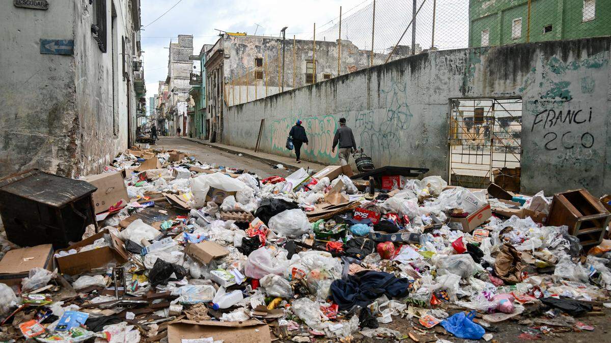 People walk past garbage discarded on a street in Havana on February 4, 2026. 