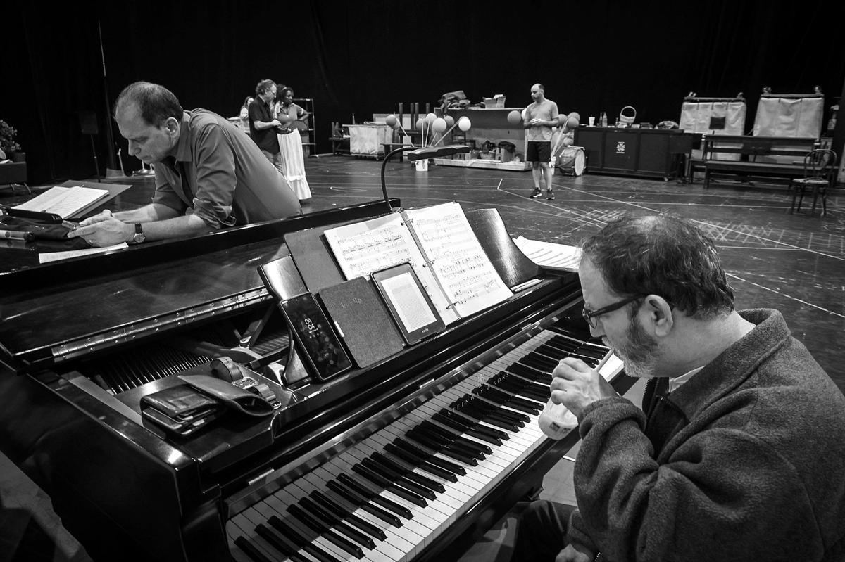 Conductor Gregory Buchalter, left, checks his phone and pianist Paul Schwartz takes in a quick read during a short break as director Jeffrey Marc Buchman (rear-left) and Kearstin Piper Brown (rear-center) rehearse with cast members of ‘I pagliacci’ at the Balfe Rehearsal Hall in Doral, Florida.