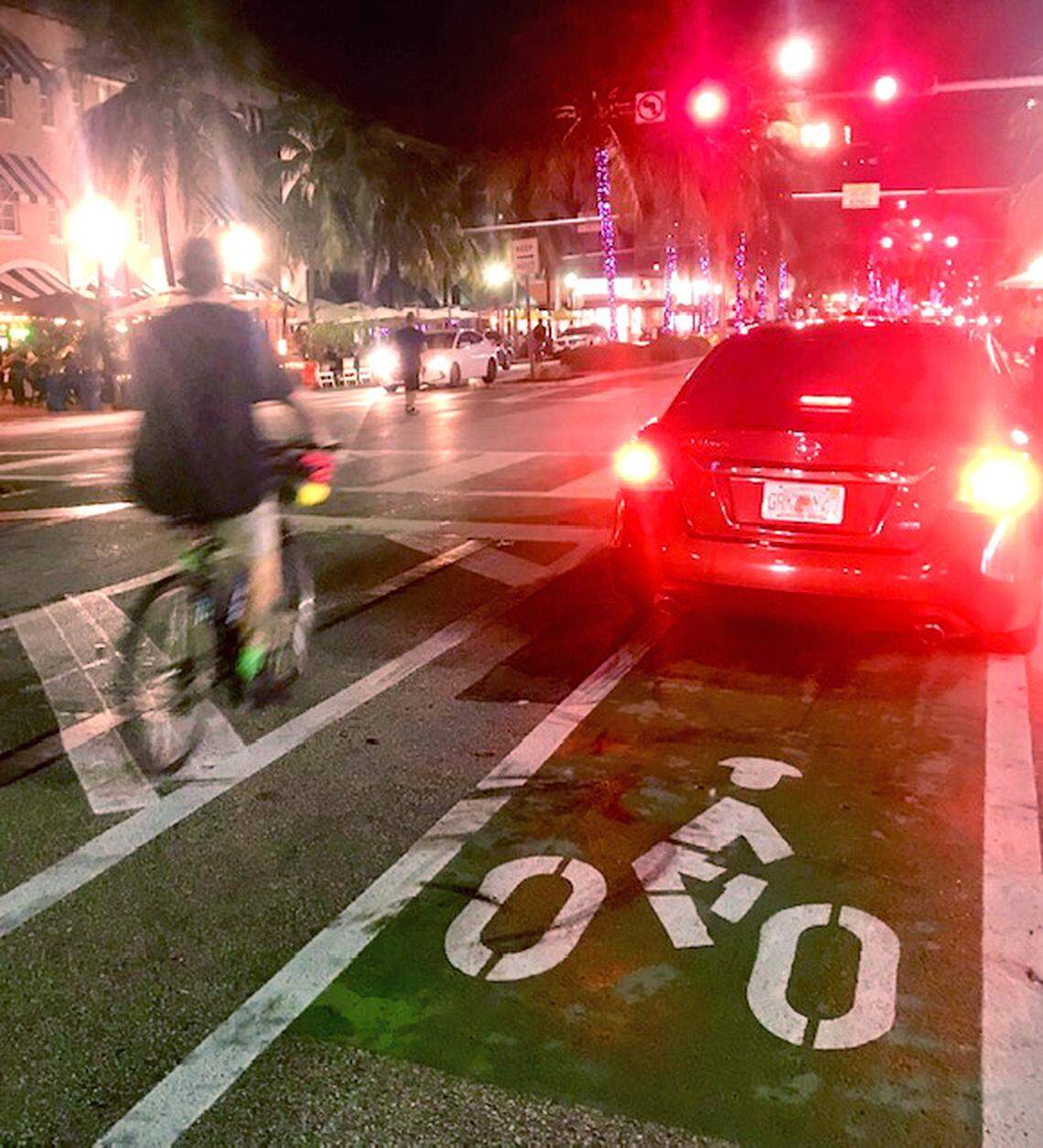 A car blocks the new bike lane on Washington Avenue in Miami Beach, forcing a cyclist to steer around it.